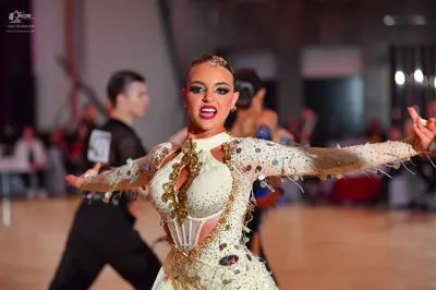 Dancesport competitor: Female dancer: champagne-colored Latin dance dress with long sleeves, heavily em