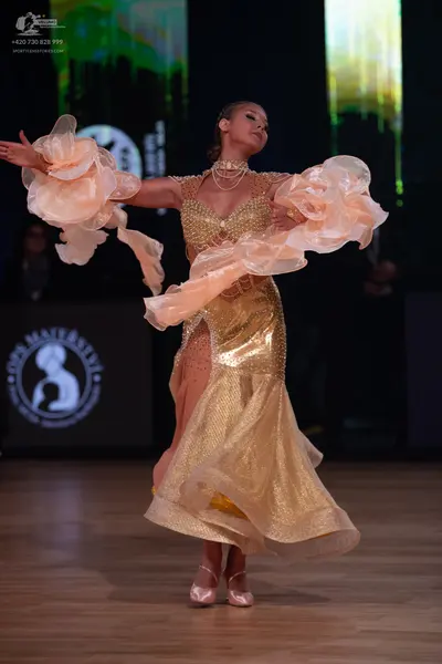 Dancesport competitor: Female dancer: gold sequined ballroom dress with a high neckline and voluminous,