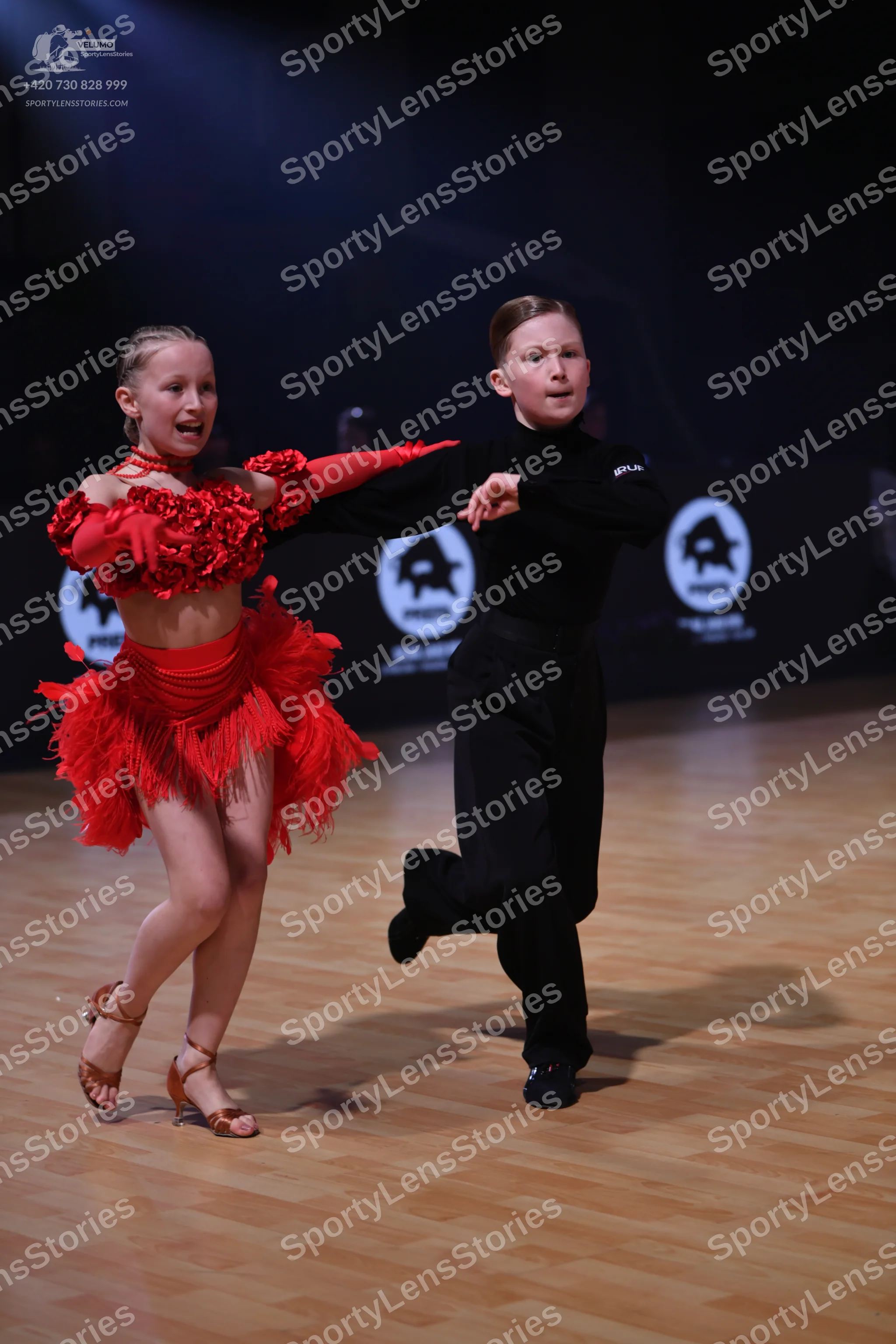 Dancesport competitor: Female dancer: red latin dress with a textured, ruffled top and a long fringe sk
