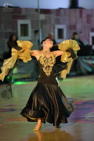 Dancesport competitor: Female dancer: black ballroom dress with gold ornate embroidery on the bodice, a
