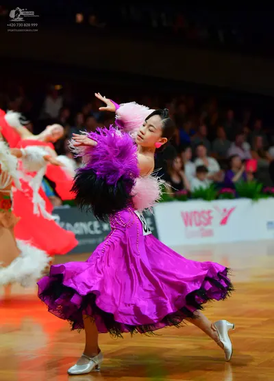 Dancesport competitor: Female dancer (foreground): bright pink satin ballgown with large black and pink