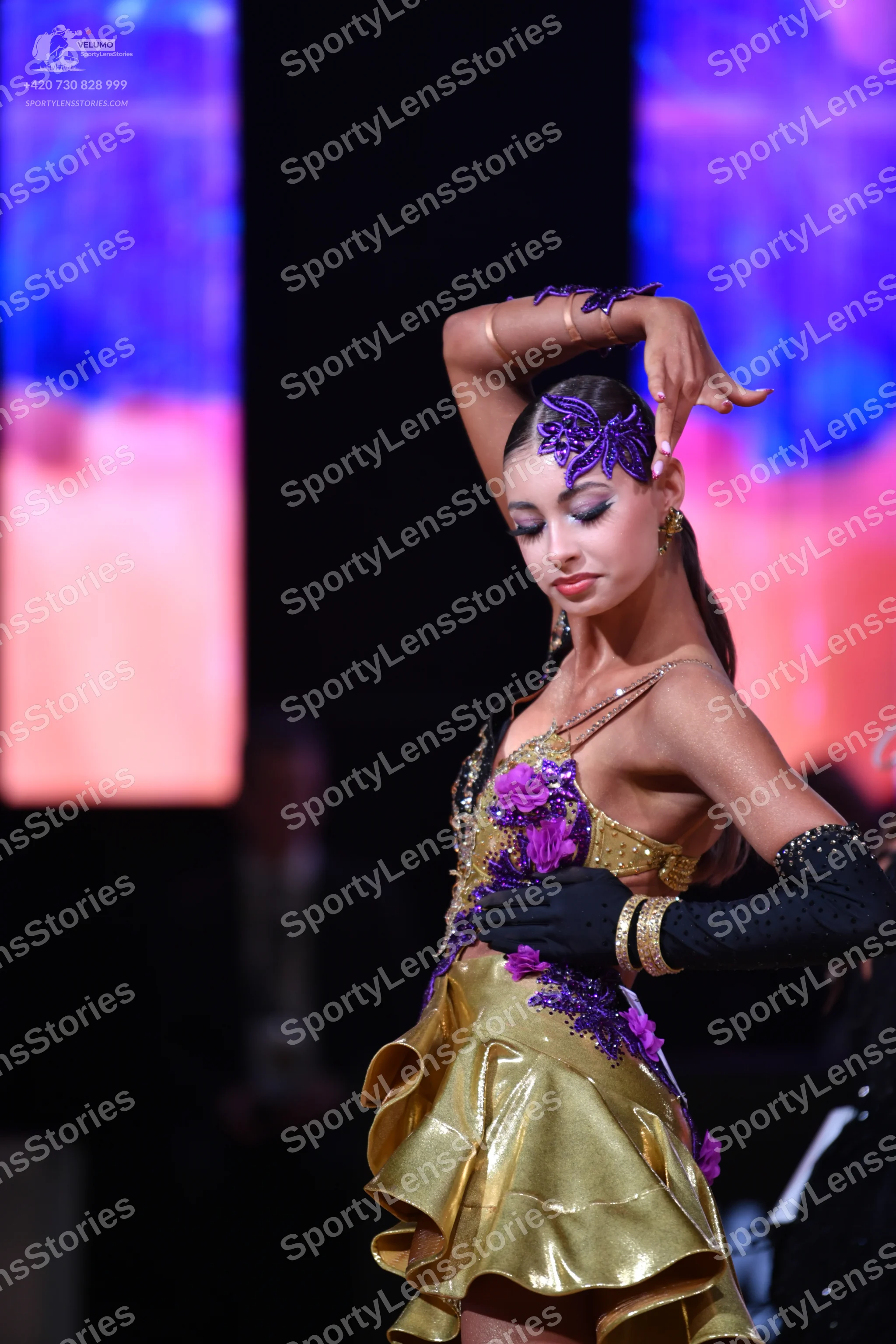 Dancesport competitor: Female dancer: gold satin Latin dress with purple floral lace appliqués and a la