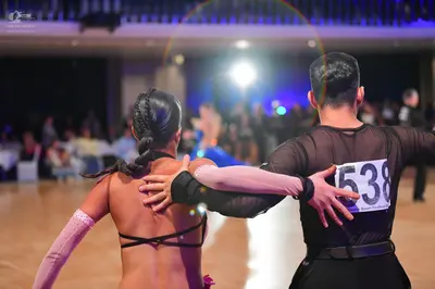 Dancesport competitor #538: Female dancer: black top with thin black straps and long, light pink sleeves