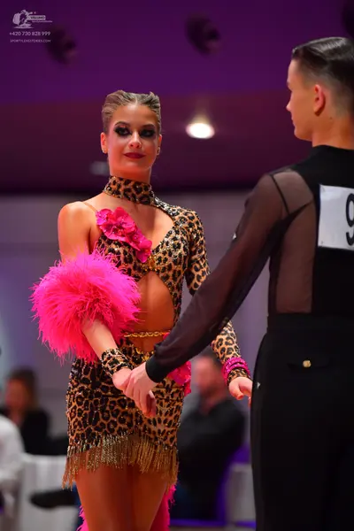 Dancesport competitor: Male dancer: black latin dance top with sheer mesh sleeves and black trousers