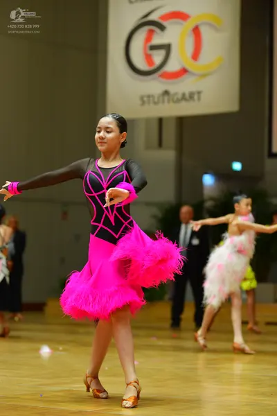 Dancesport competitor: Central female dancer: black long-sleeved Latin dress with bright pink piping on