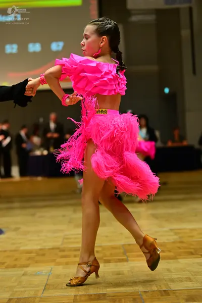 Dancesport competitor: Female dancer: bright pink Latin dance costume consisting of an off-the-shoulder