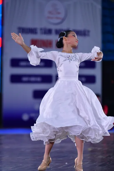 Dancesport competitor: ** Female: White latin dress with long, flowing sleeves and a bodice heavily emb