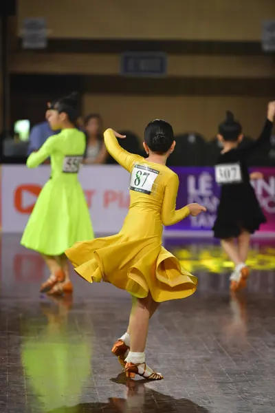Dancesport competitor #87, #407: Female dancer: bright yellow long-sleeve latin dress with a full, flowing skirt
