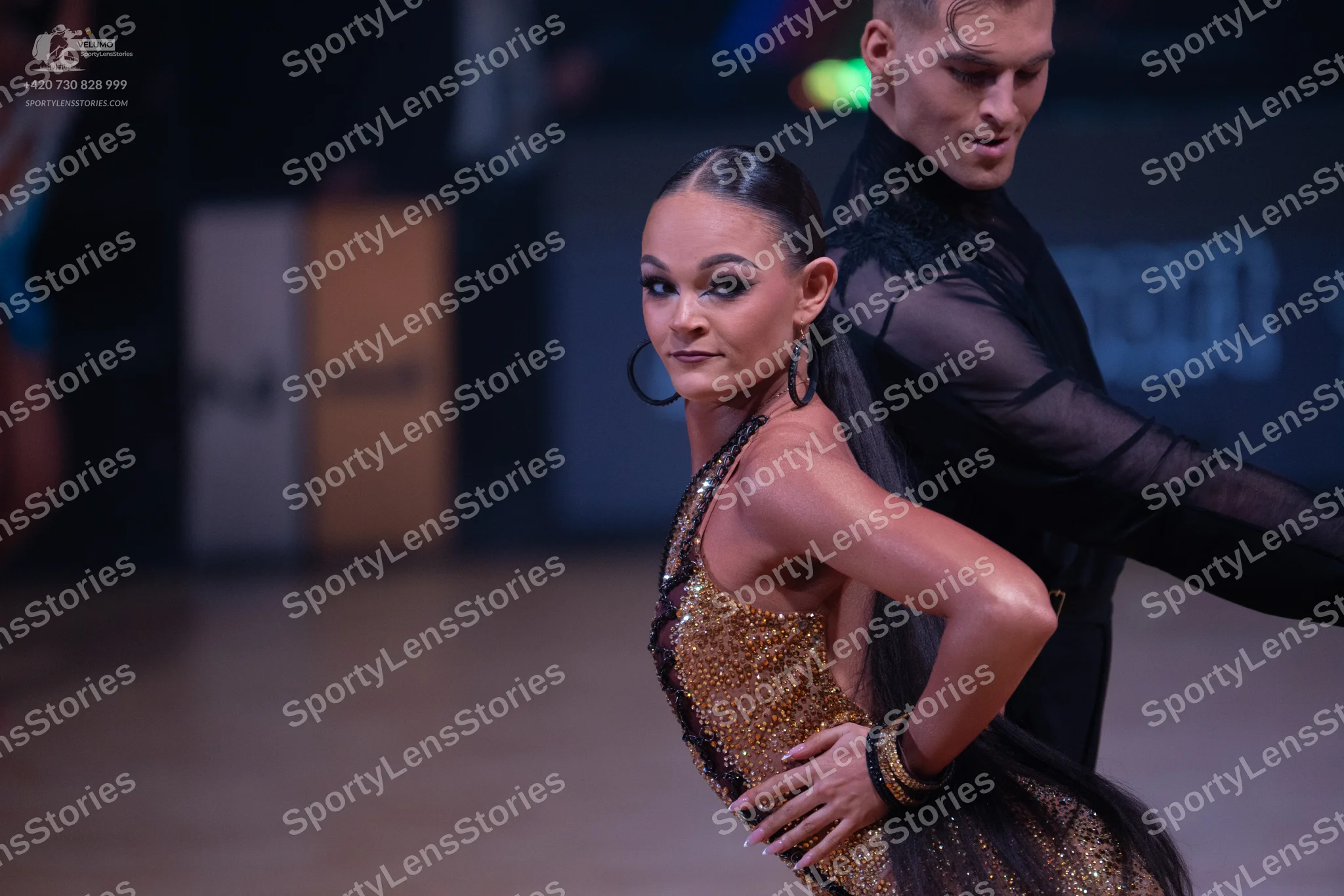 Dancesport competitor: Female dancer: gold sequined one-shoulder latin dress and large hoop earrings