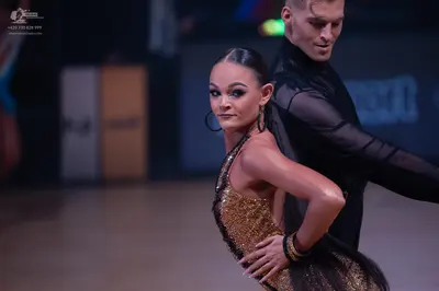 Dancesport competitor: Female dancer: gold sequined one-shoulder latin dress and large hoop earrings