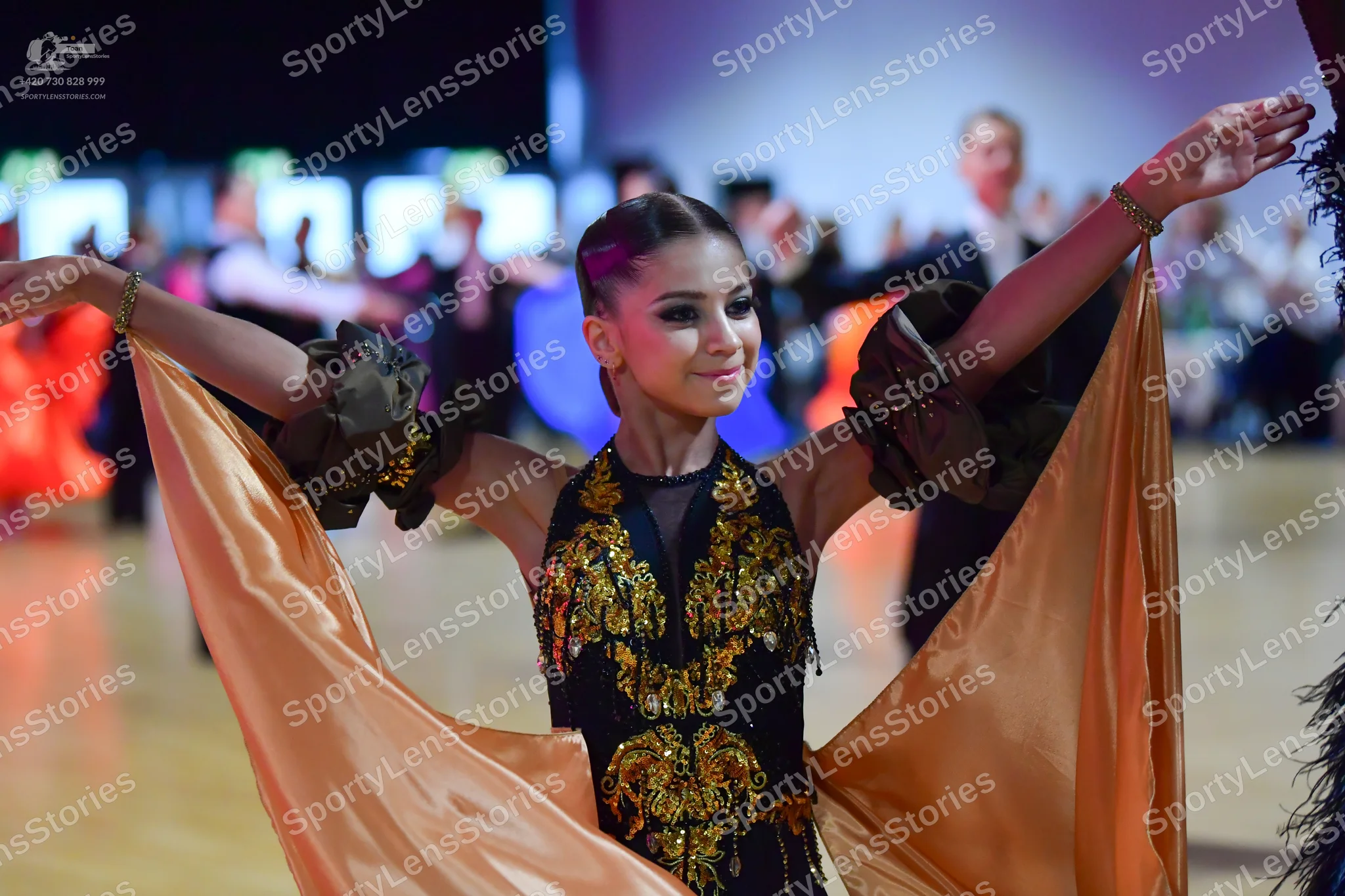 Dancesport competitor: Female dancer: black Latin dance dress with elaborate gold sequined/embellished