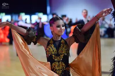 Dancesport competitor: Female dancer: black Latin dance dress with elaborate gold sequined/embellished 