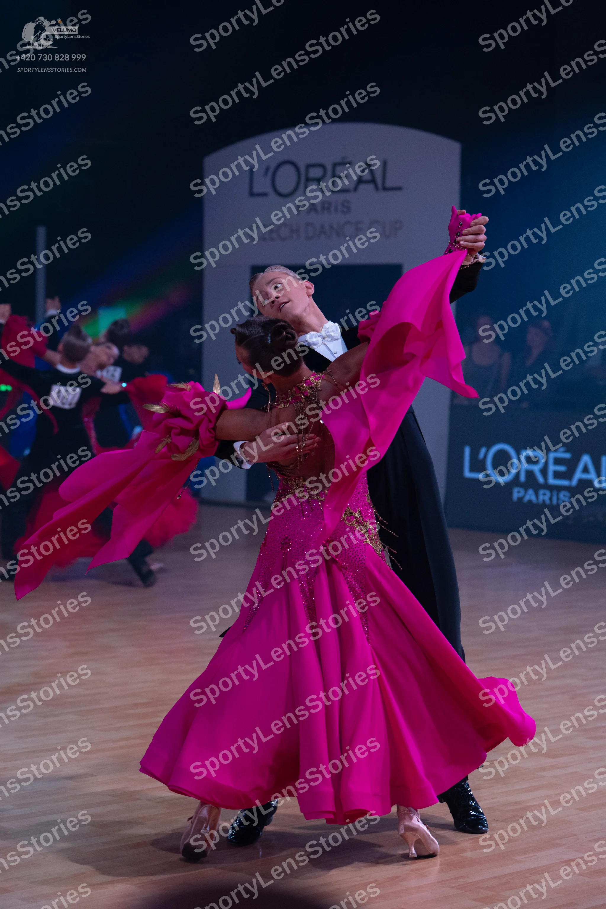 Dancesport competitor: Female dancer: bright pink ballgown with an embellished bodice and large, flowin