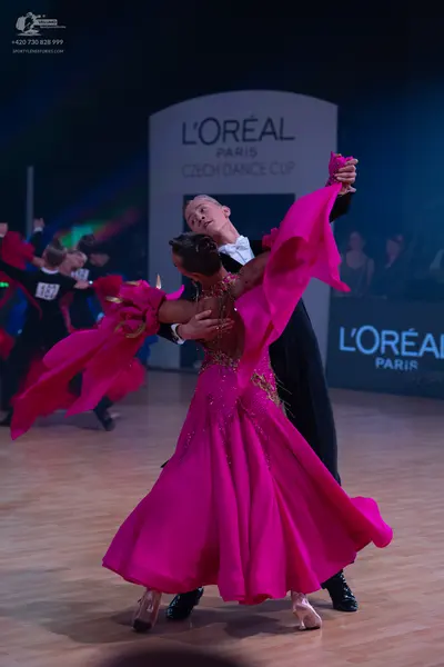 Dancesport competitor: Female dancer: bright pink ballgown with an embellished bodice and large, flowin