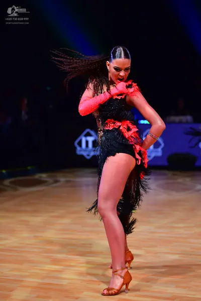 Dancesport competitor: Female dancer: black latin dress with heavy black fringe and red floral fabric e