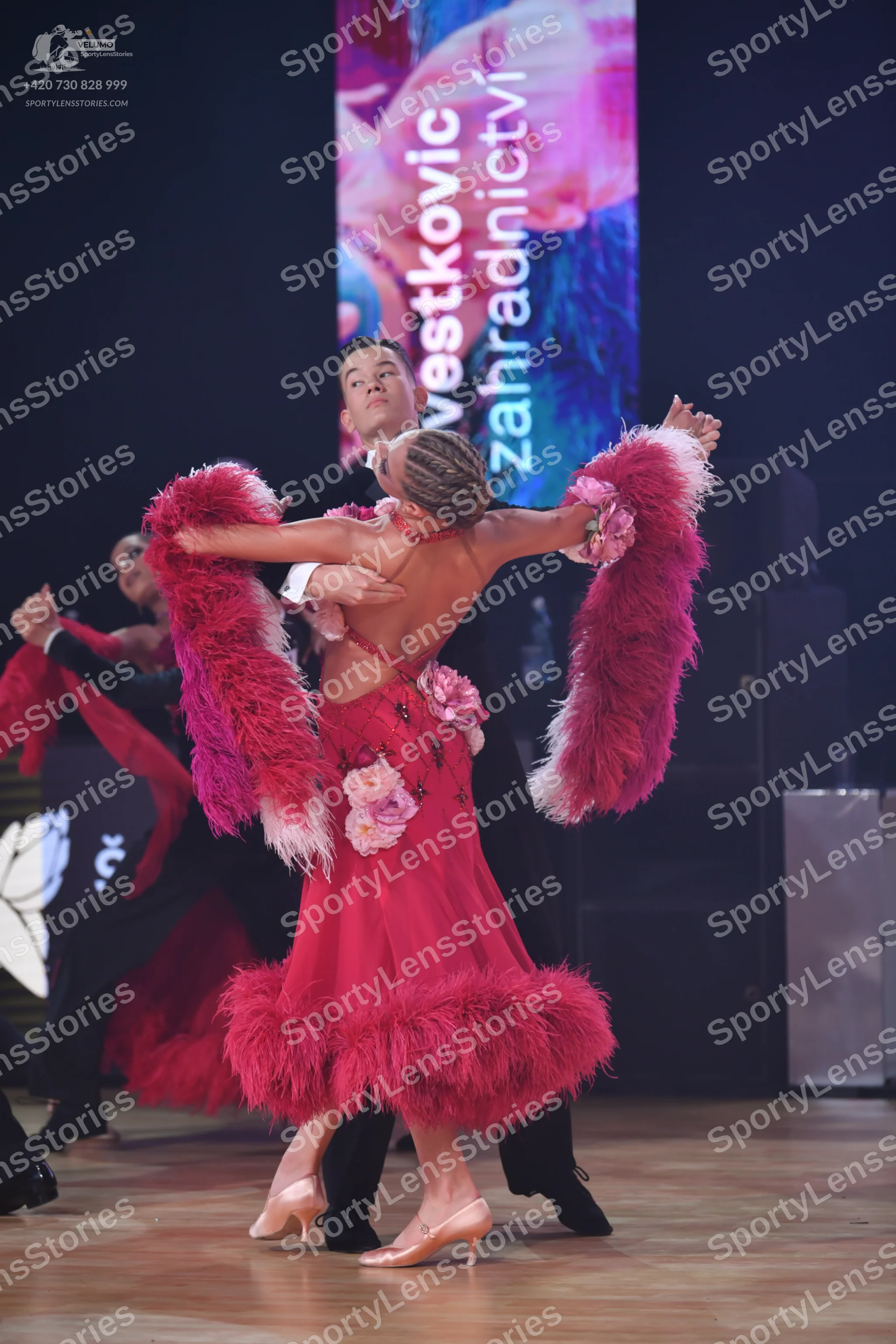 Dancesport competitor: Female dancer: fuchsia Latin dress with heavy feather trim on the skirt and larg