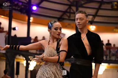 Dancesport competitor: Male dancer: black open-chested shirt, black trousers, and a silver pendant neck