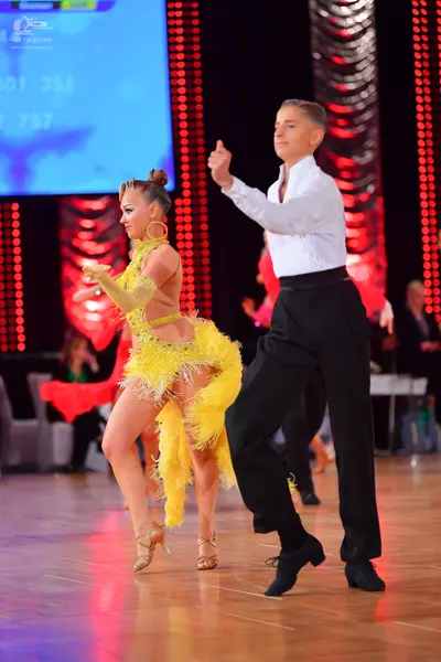 Dancesport competitor: Female dancer: yellow latin dress with fringe, gold long gloves, and large gold 