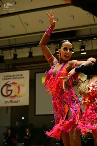 Dancesport competitor: Female dancer 1: bright pink latin dress with long fringe and sequins, with matc