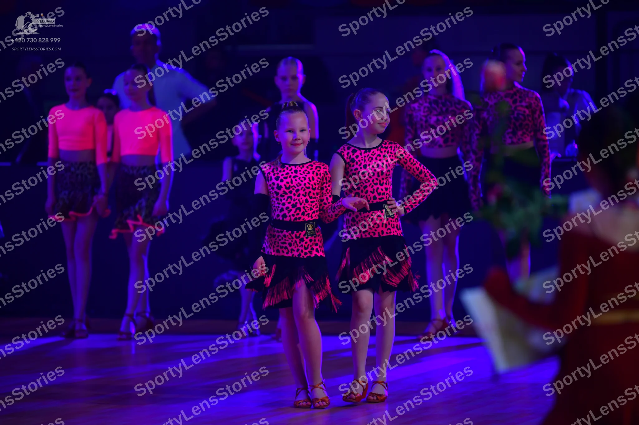 Dancesport competitor: The main group of dancers is wearing matching Latin-style costumes consisting of