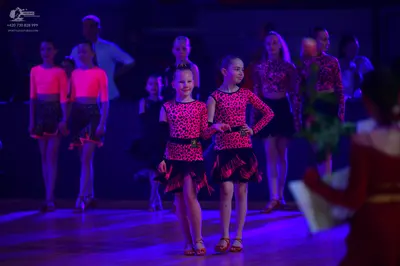 Dancesport competitor: The main group of dancers is wearing matching Latin-style costumes consisting of