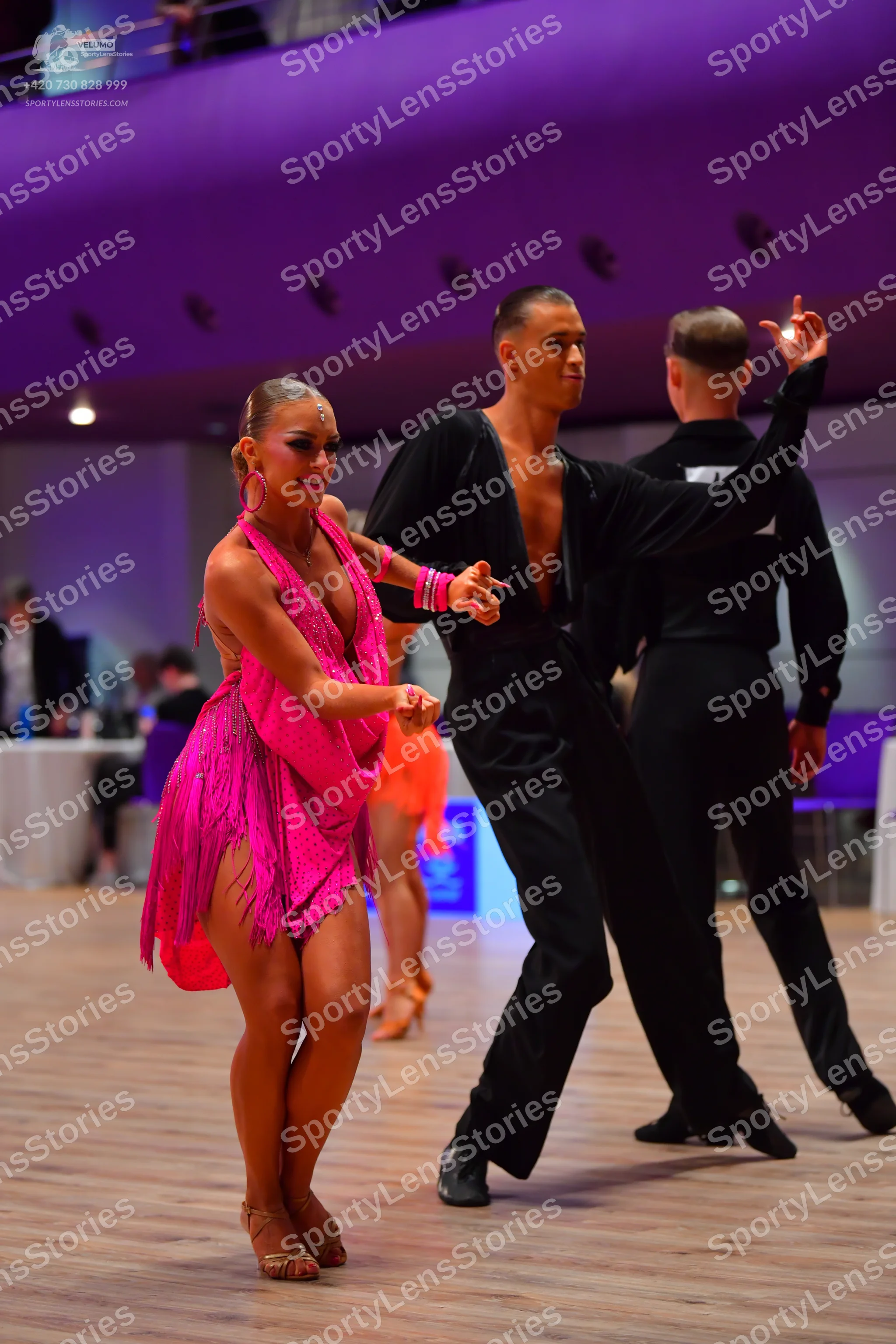 Dancesport competitor: Female dancer: pink latin dress with fringe, hoop earrings, and pink dance shoes