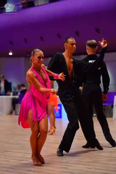 Dancesport competitor: Female dancer: pink latin dress with fringe, hoop earrings, and pink dance shoes