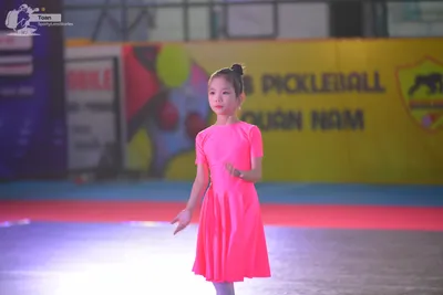 Dancesport competitor: ** Female: Light pink, sleeveless, A-line dress made of what appears to be a sli