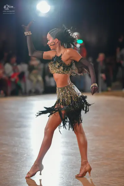 Dancesport competitor: Female dancer: black and gold Latin dance costume featuring a sequined/beaded cr