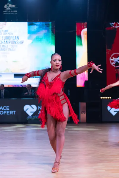 Dancesport competitor: Female dancer: red Latin dress with fringe and sequins, with matching red armban