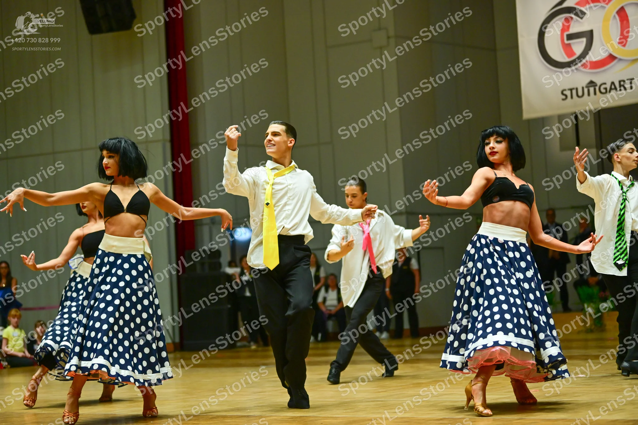 Dancesport competitor: Female dancers: black bra-style tops, white waistbands, and long navy blue skirt