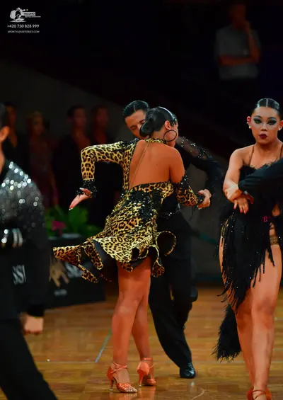 Dancesport competitor: Female dancer in foreground: leopard print latin dress with long sleeves and bla