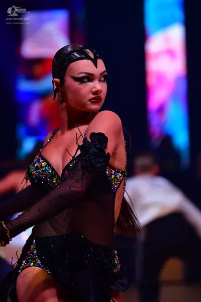 Dancesport competitor: Female:** Black, form-fitting latin dress with intricate, multi-colored (red, go