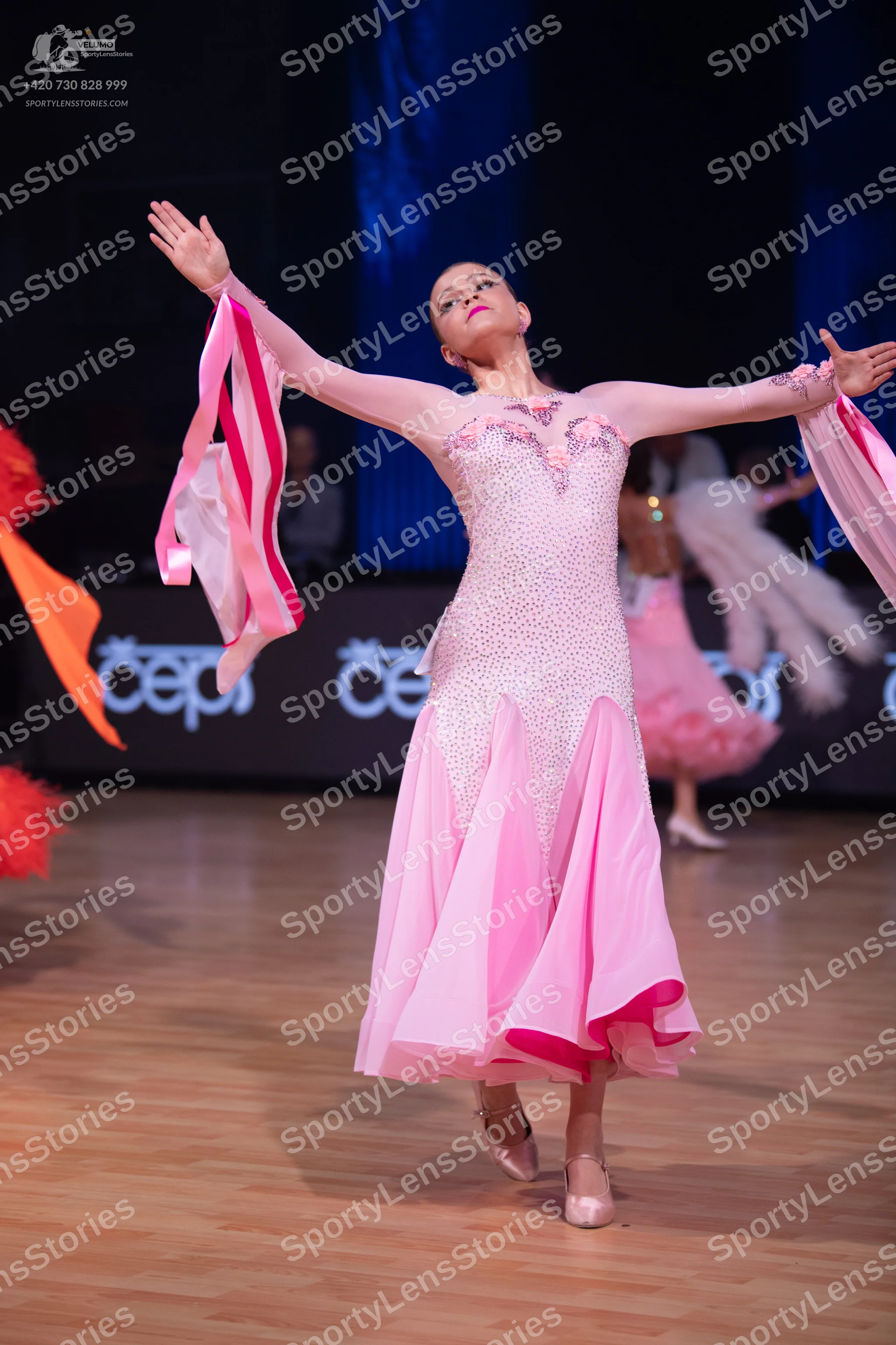 Dancesport competitor: Main female dancer: light pink Latin dress with long sleeves, a sequined bodice,