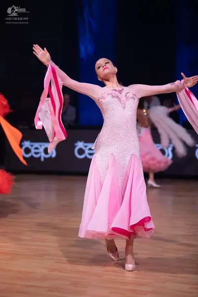 Dancesport competitor: Main female dancer: light pink Latin dress with long sleeves, a sequined bodice,