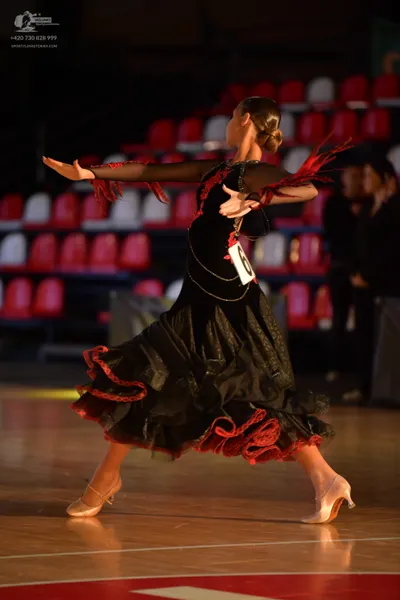 Dancesport competitor: Female dancer: black latin dress with red ruffles and fringe on the sleeves and 