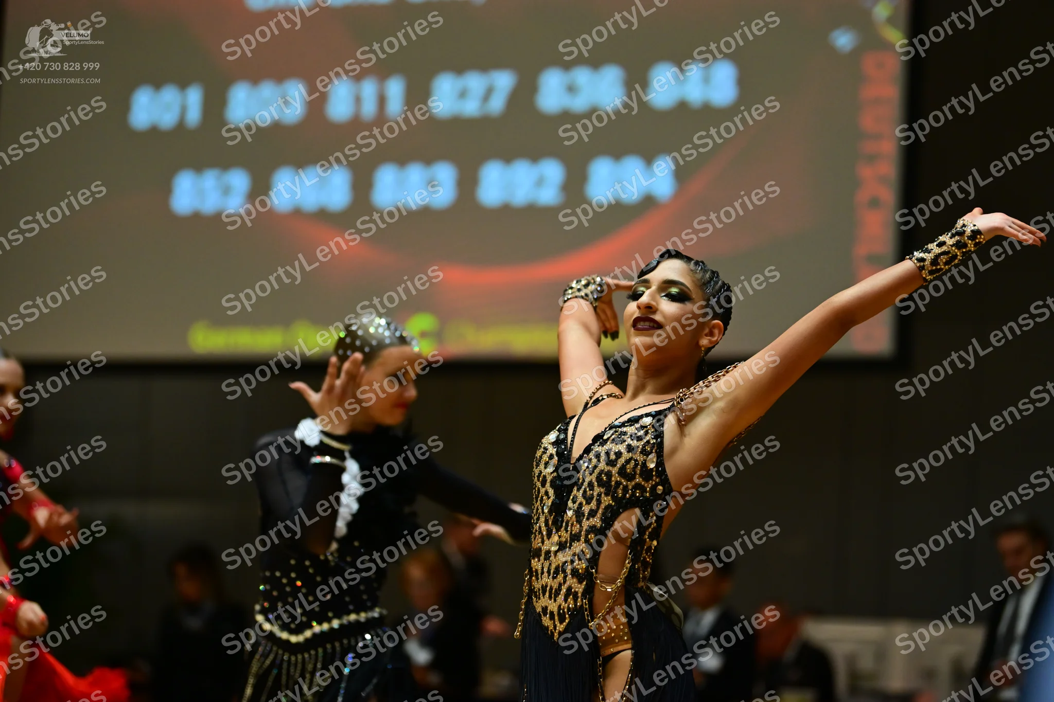 Dancesport competitor: Female dancer in foreground: leopard print latin dance costume with sparkly embe