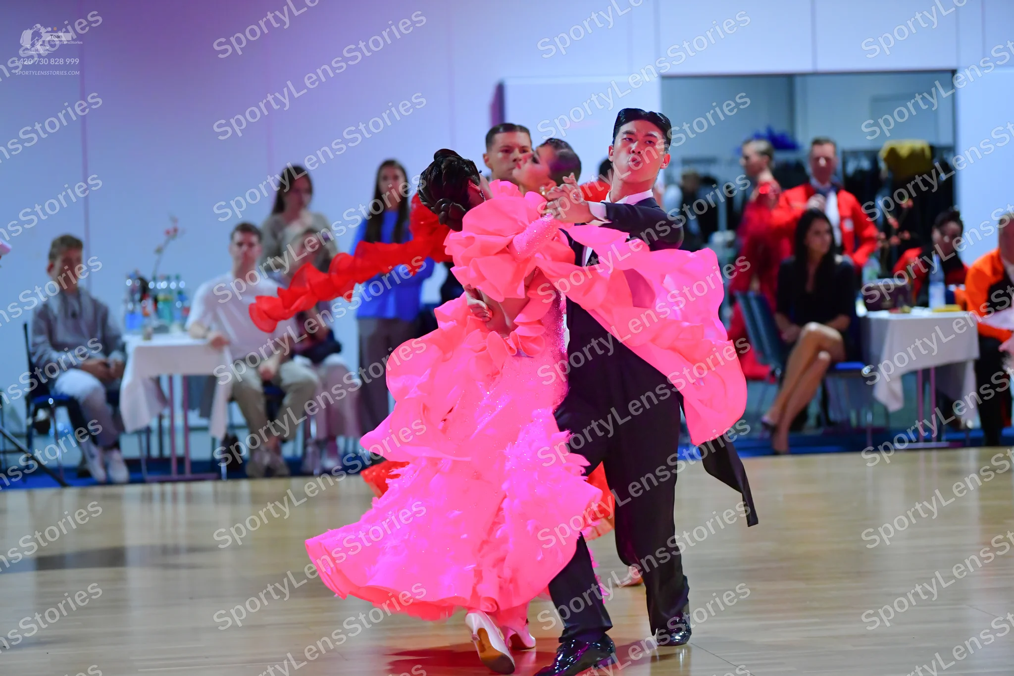 Dancesport competitor: Female dancer: voluminous hot pink ballroom dress with many layers of ruffled fa