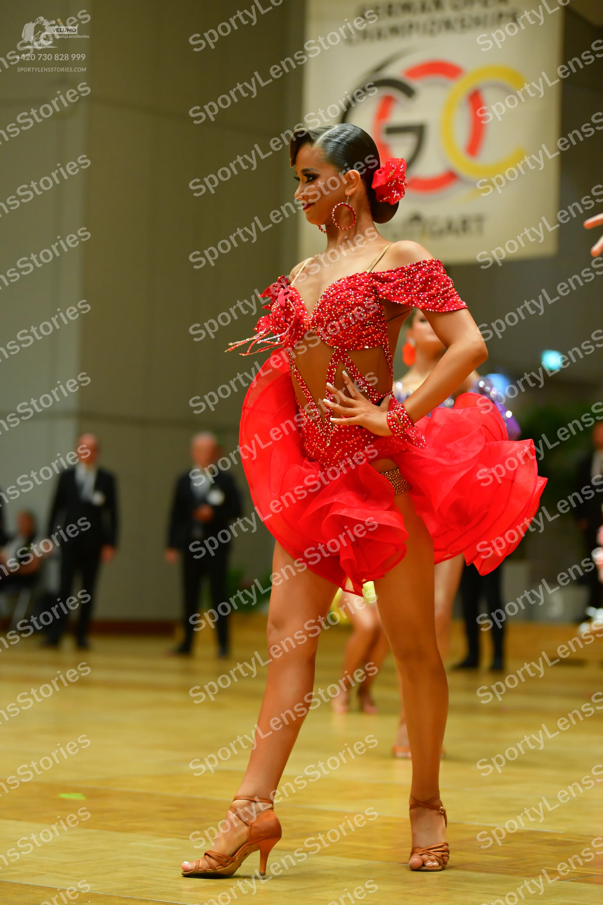 Dancesport competitor: Female dancer: red latin dress with a sequined bodice and a ruffled, voluminous