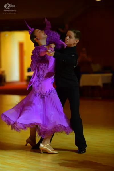 Dancesport competitor: Female dancer: long purple ballroom dress with voluminous ruffled and feathered 