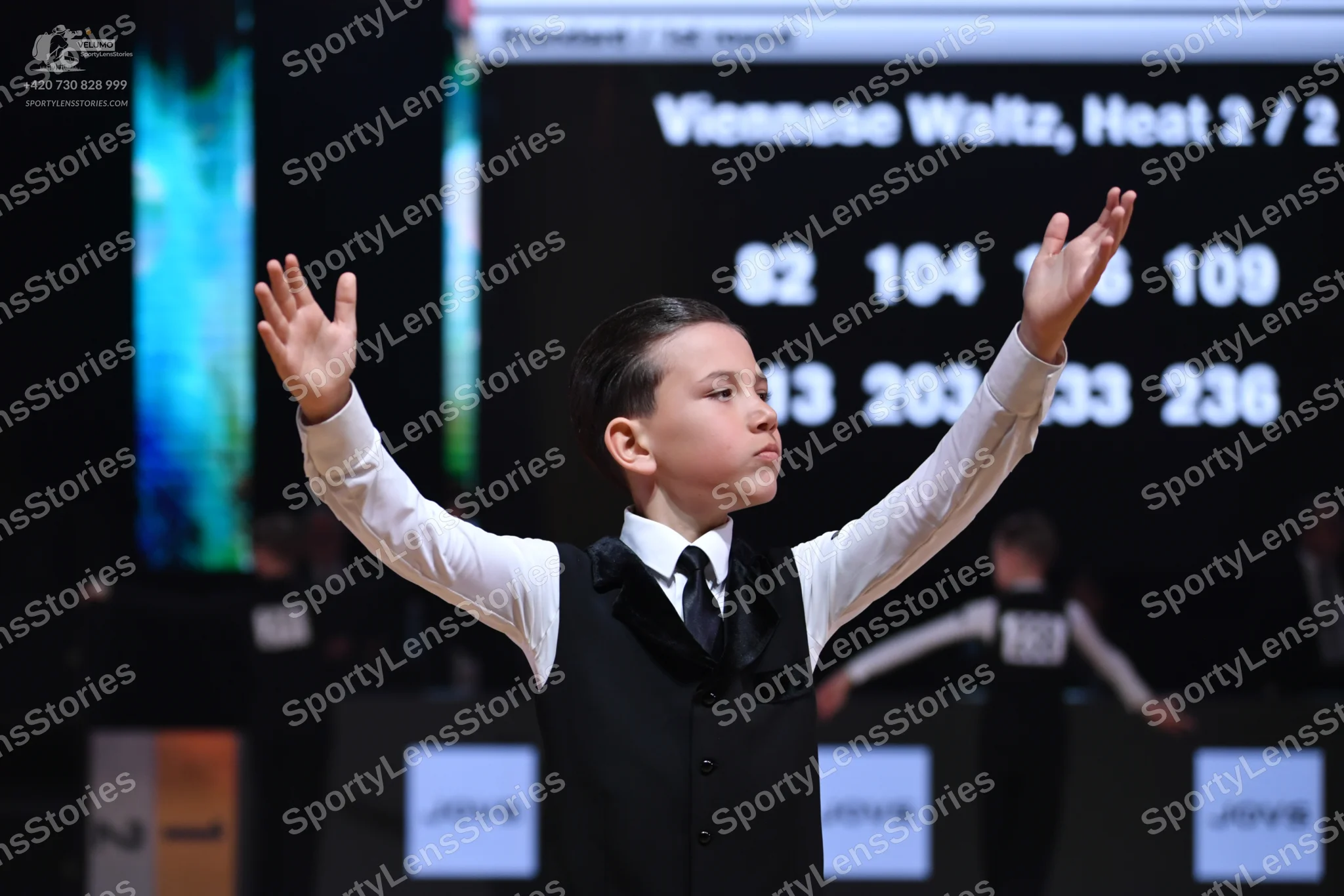 Dancesport competitor: Male dancer in foreground: white long-sleeved shirt, black waistcoat, and black