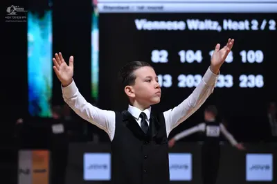 Dancesport competitor: Male dancer in foreground: white long-sleeved shirt, black waistcoat, and black 