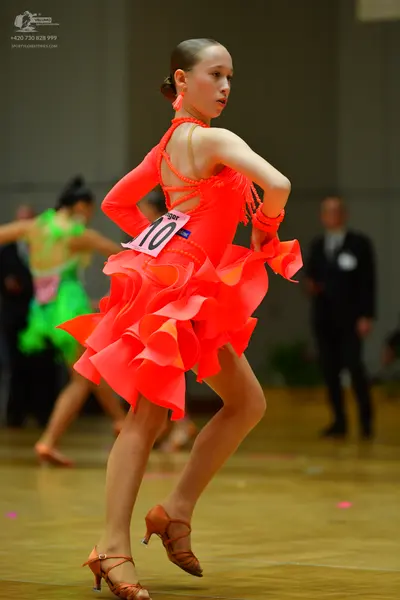 Dancesport competitor #10: Female dancer in foreground: bright orange Latin dance dress with long sleeves, 
