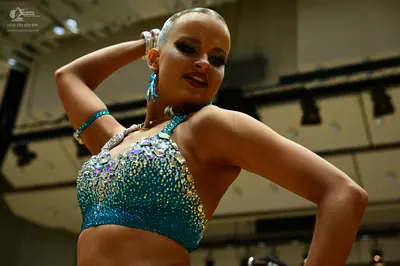 Dancesport competitor: Female dancer: teal sequined latin crop top with large teal earrings and silver 