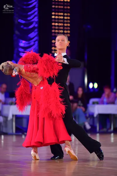 Dancesport competitor: Female dancer: long red ballroom dress with extensive red feather/fringe embelli