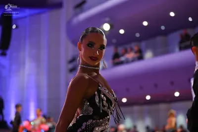 Dancesport competitor: Female dancer: black latin dress with silver sequin patterns and long fringe, we