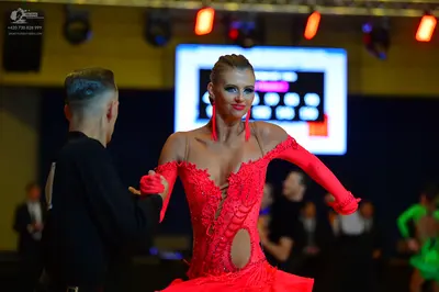 Dancesport competitor: Female dancer: red latin dress with intricate lace-like embroidery, cutouts, mat