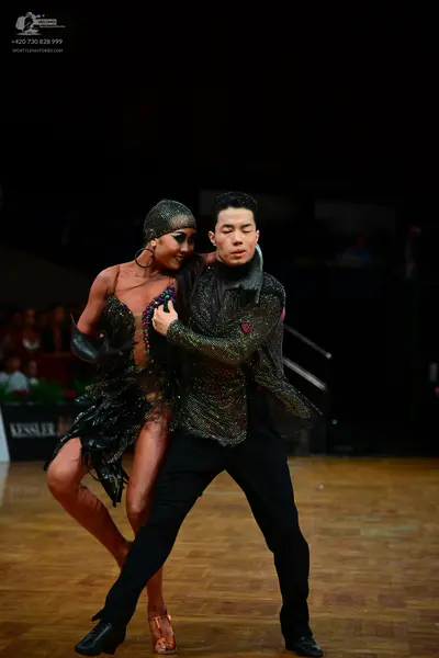 Dancesport competitor: Female dancer: dark latin dress with sequins and black fringe, matching headband