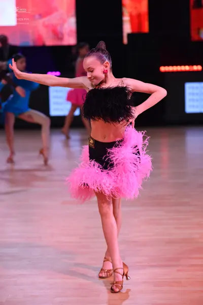 Dancesport competitor: Female dancer in foreground: black feathered top and a voluminous bright pink fe