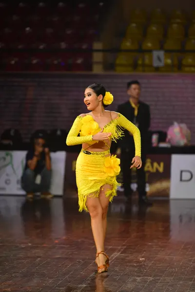 Dancesport competitor: Female dancer: bright yellow Latin dance dress with long sleeves and layered fri